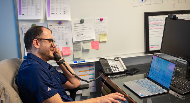 A man talking someone over the phone while staring towards his laptop.