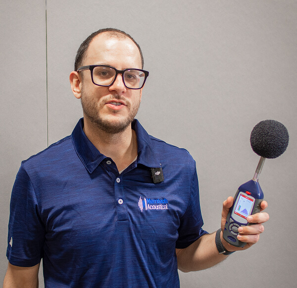 An employee of Memtech Acoustical holding a decibel test microphone.