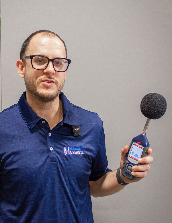 An employee of Memtech Acoustical holding a decibel test microphone.