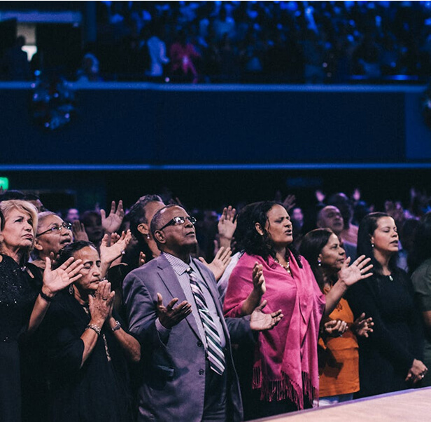 A group of people with their hands spread out, solemnly praying.