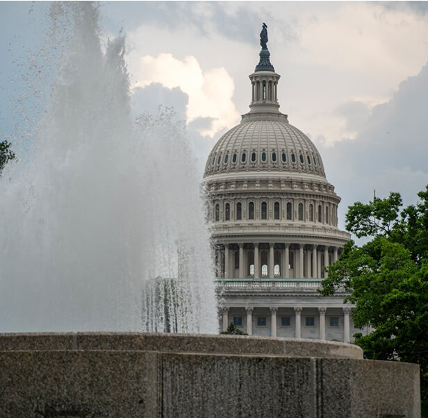 A shot of the fountain with a building with pointed roof behind.