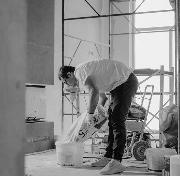 A man opening a cement sack inside the building still under construction.