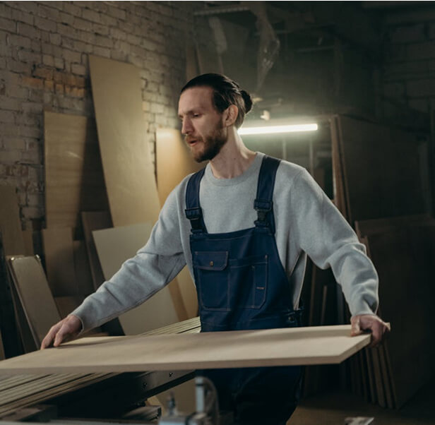 A man holding a plywood inside a room.