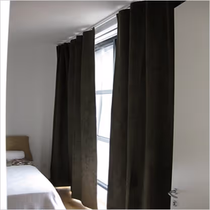 An empty bedroom with black curtains.