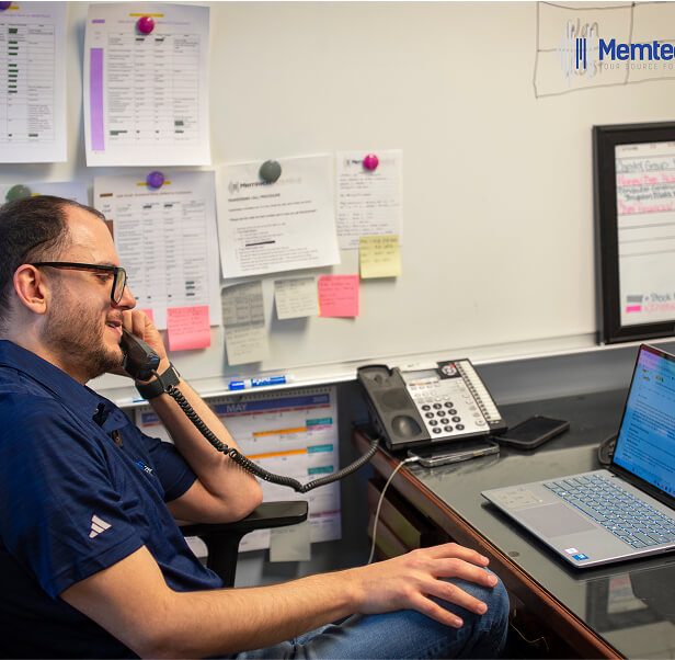 A man talking over the telephone while working with his laptop.