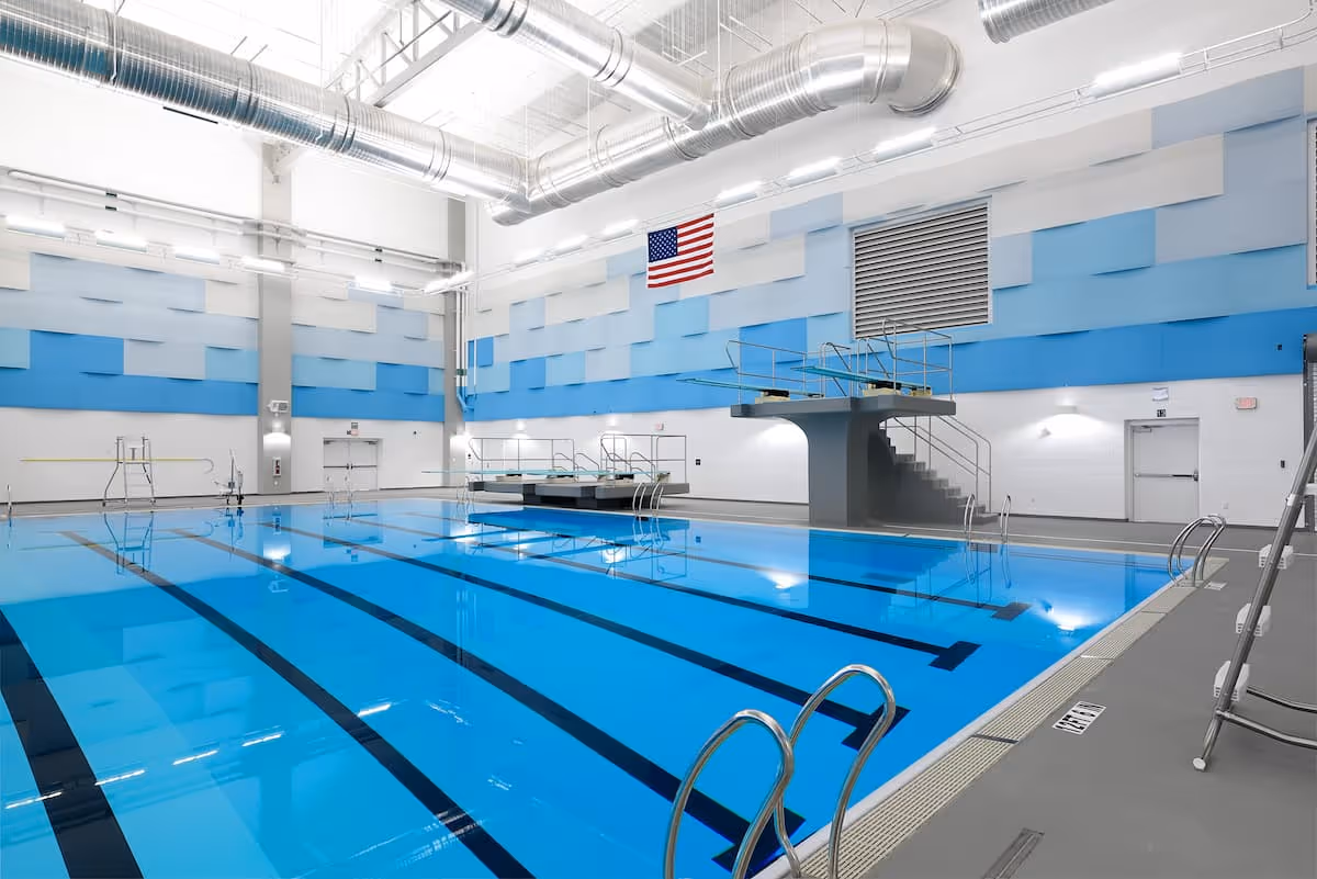 Indoor swimming pool facility with diving platforms and custom blue acoustic wall panels designed to reduce reverberation in large aquatic environments
