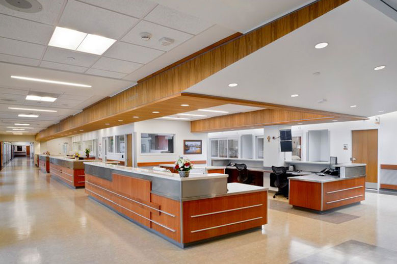 Hospital reception area with acoustic ceiling treatments and wood accents, demonstrating healthcare noise control for patient comfort and privacy.