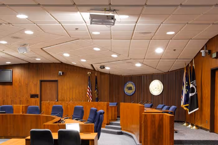 City council chamber with acoustic ceiling panels and wood-paneled walls, illustrating municipal noise control in government buildings.