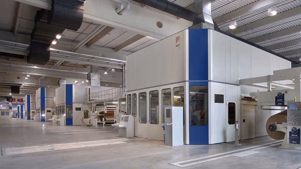 Industrial acoustic enclosure surrounding large machinery in a manufacturing facility for effective noise isolation and worker protection.