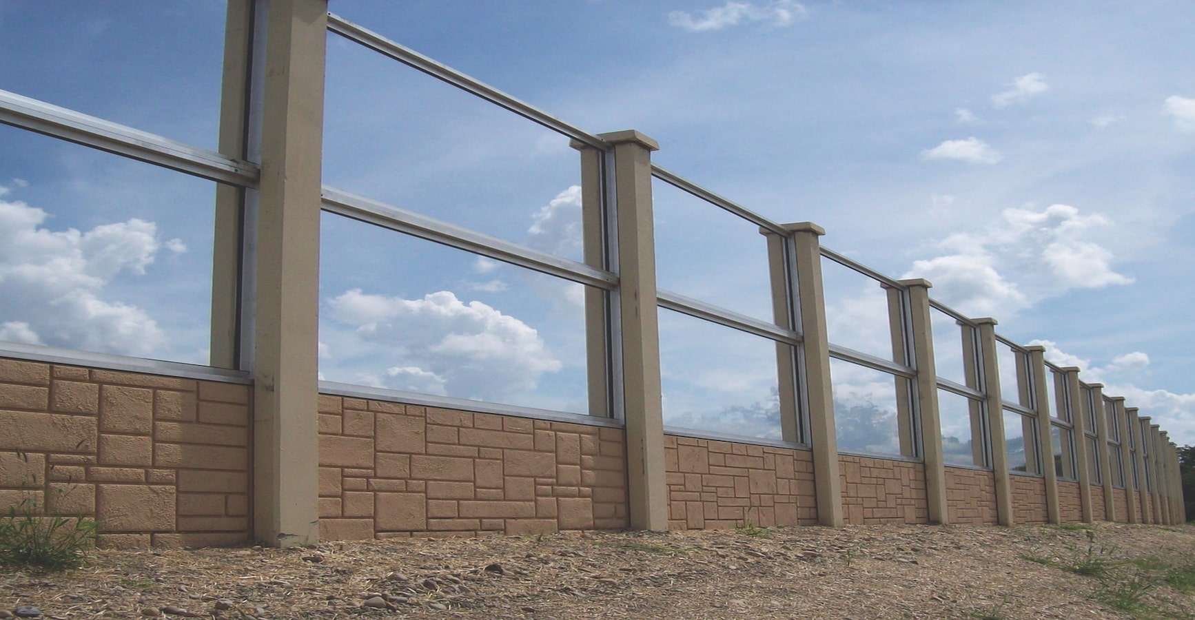 Combination sound barrier wall with concrete base and transparent upper panels designed for highway or transportation noise control.