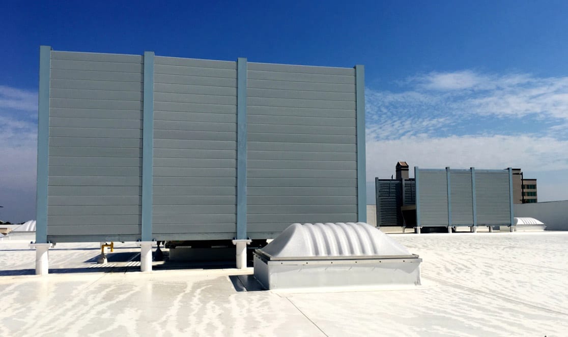 Rooftop-mounted acoustic barrier walls enclosing mechanical HVAC units, minimizing noise pollution for surrounding buildings.