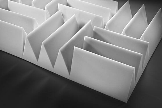 White acoustic baffle panels arranged in a zigzag pattern, designed to absorb sound and reduce reverberation in large open spaces.