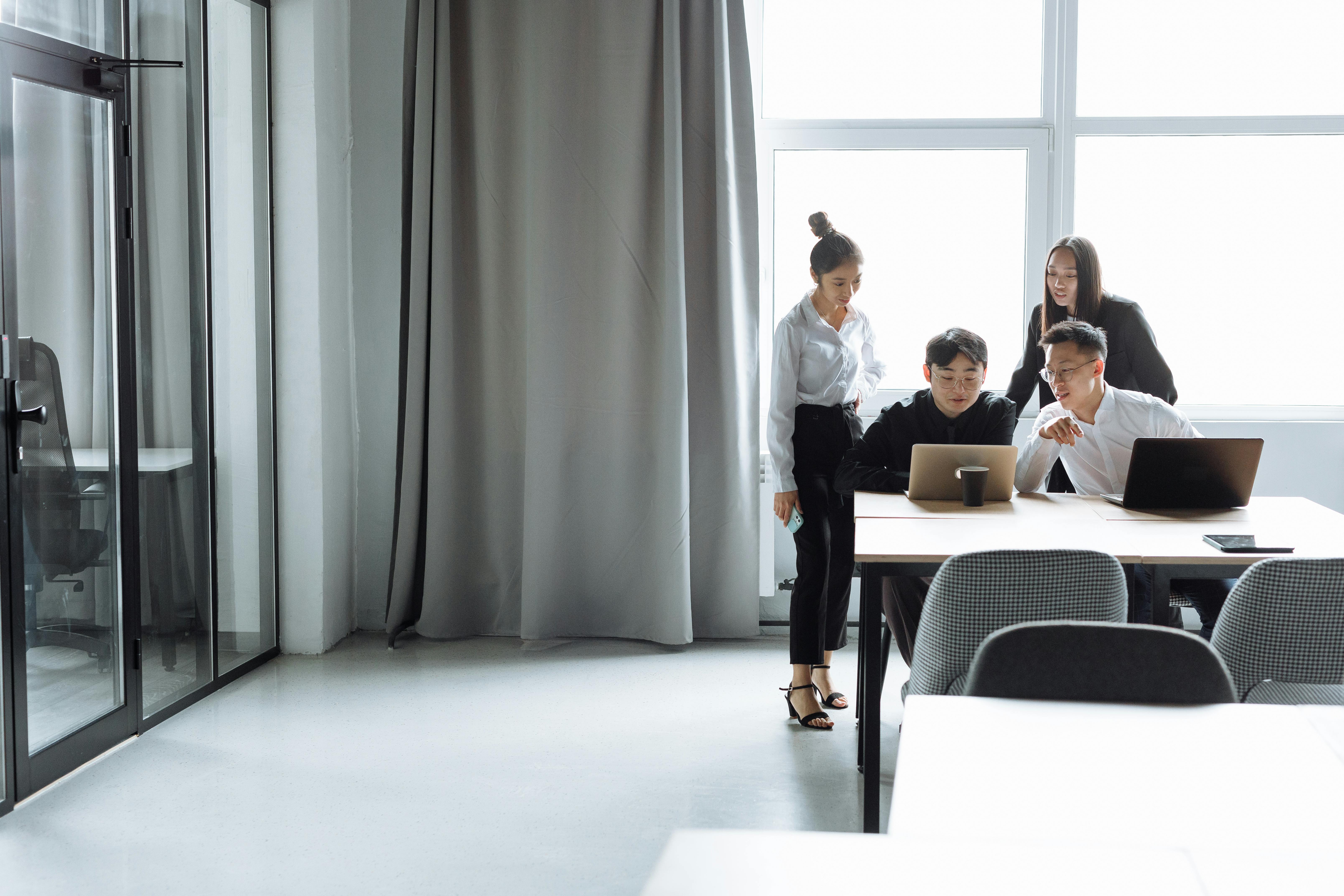 Modern office meeting room with large acoustic curtains and a group of professionals collaborating at a table.