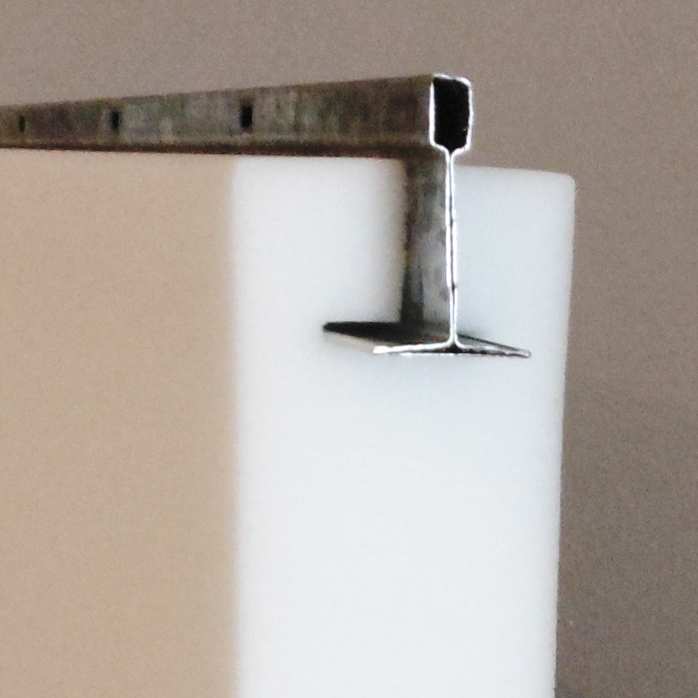 Close-up of a metal T-shaped rail attached to a white foam block.