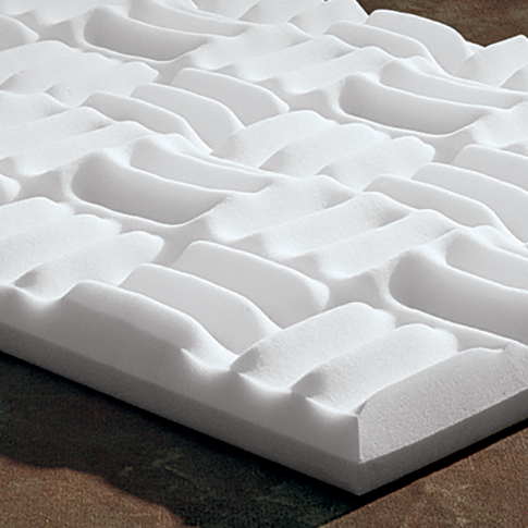 White foam sound-absorbing panel with an irregular, wavy surface texture on a brown surface.