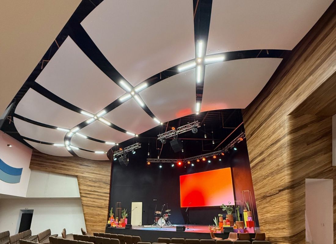 Ovation Acoustical Reflector and Diffuser by Kinetics Noise Control, white satin gel-coat reflector panels suspended above a performance hall stage.