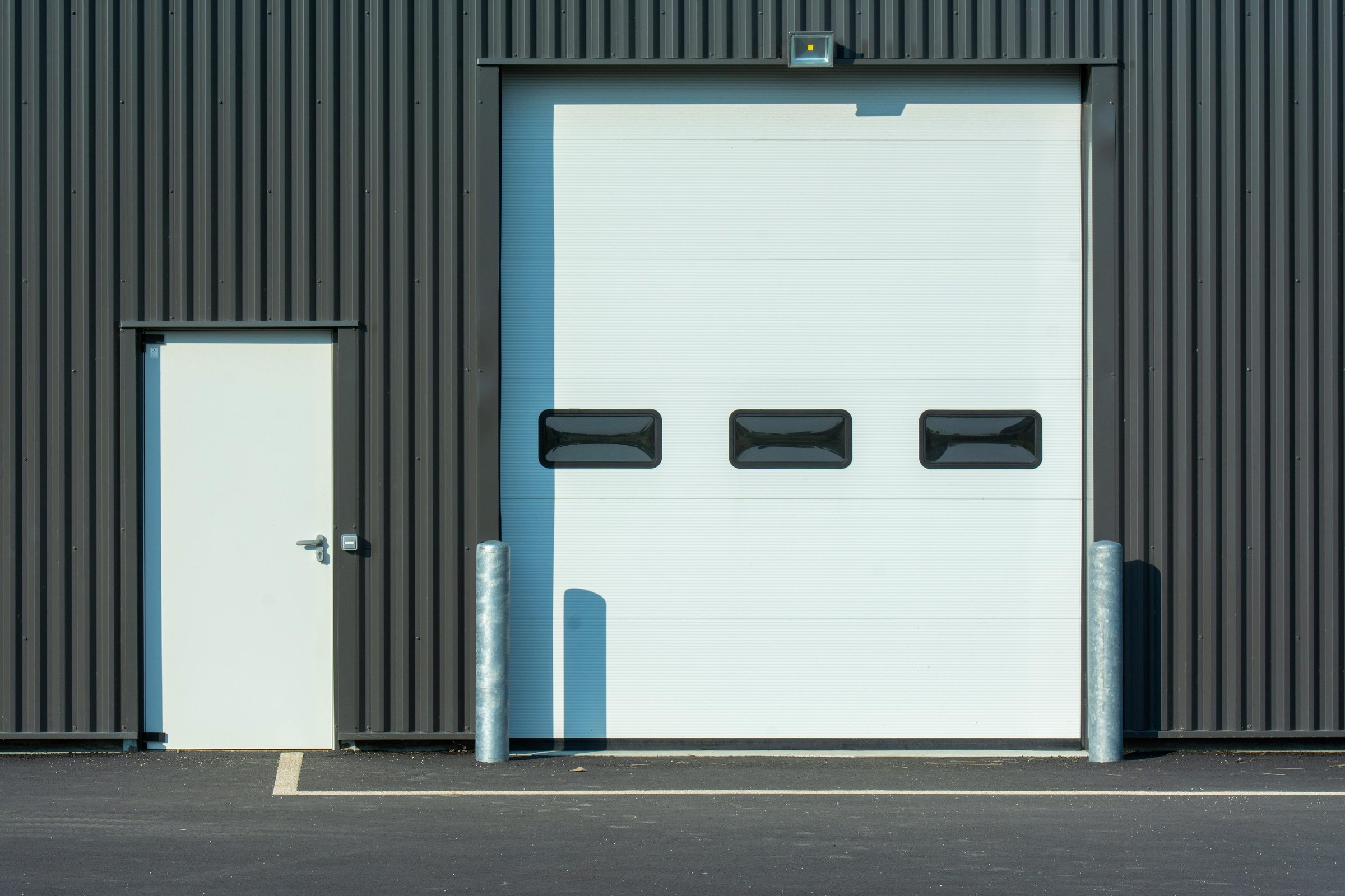 Exterior of a completed commercial building envelope with an insulated overhead dock door and a personnel entry door.