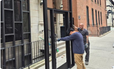2 men holding empty door frame on a sidewalk
