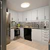 Kitchen remodel in Houston with white cabinets, stainless steel refrigerator, black dishwasher, and tiled backsplash.