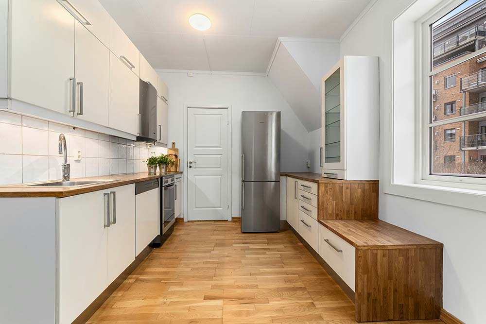 Kitchen remodel in Los Angeles with white cabinets, wooden countertops, stainless steel appliances, and light wooden flooring.