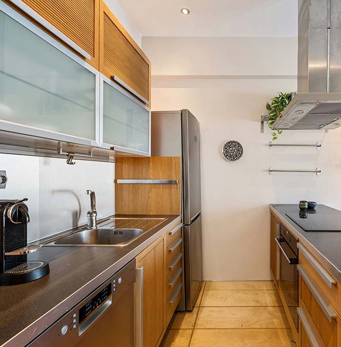 Kitchen remodel in Los Angeles with wooden cabinets, stainless steel appliances, a sink, and a stovetop with a range hood.