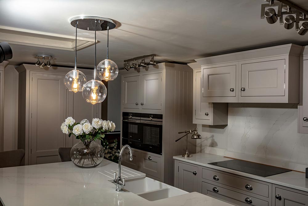 Kitchen remodel in Chicago with beige cabinetry, marble countertops, a vase of white flowers, pendant lights, and built-in ovens.
