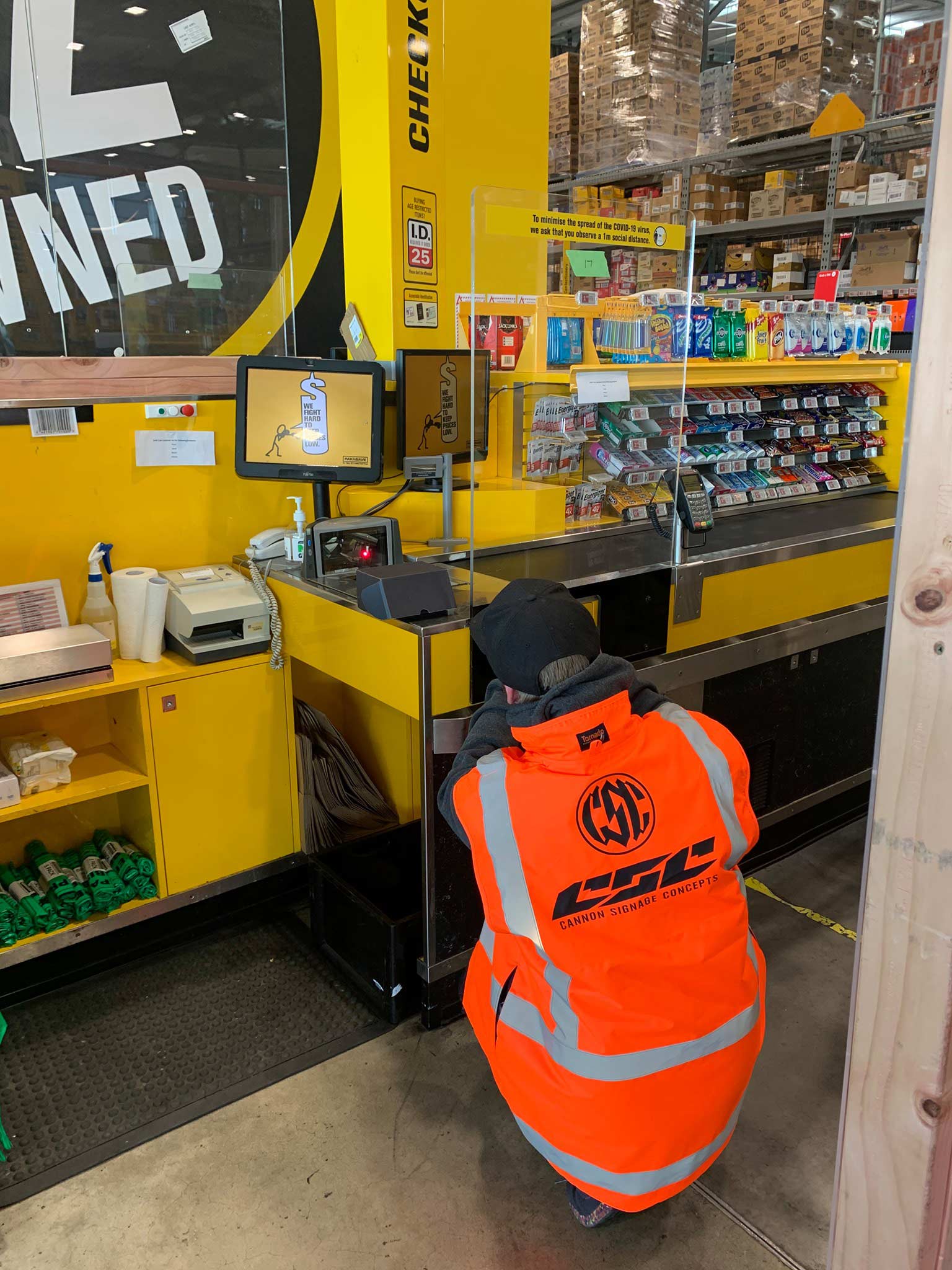 Expert signage installation at a retail store checkout, highlighting Cannon Signage Concepts' comprehensive solutions for branding and wayfinding in Auckland's corporate sector. Cannon Signage Concepts