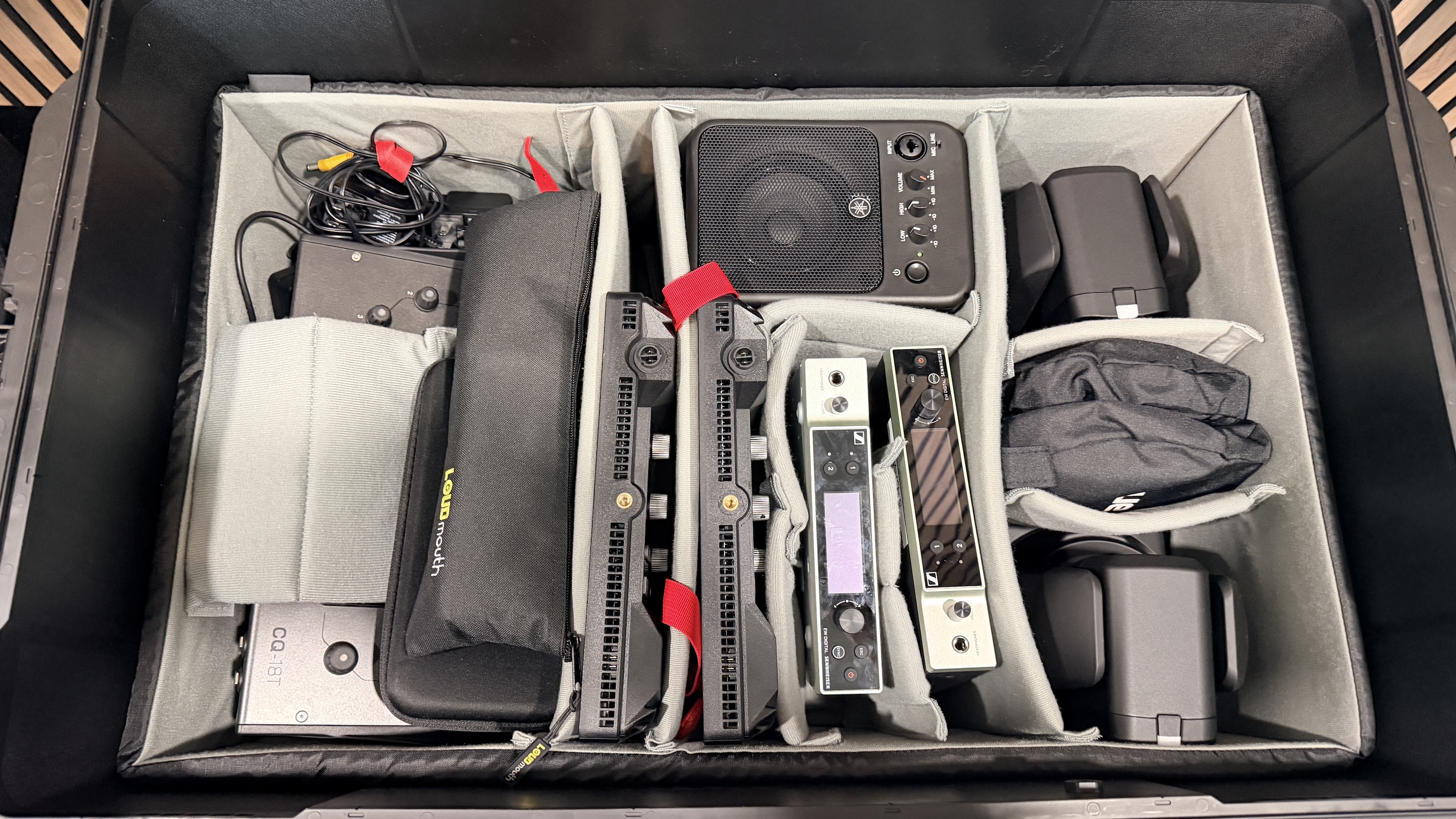 Organized Pelican case with professional audio interfaces, wireless receivers, and cables ready for event setup