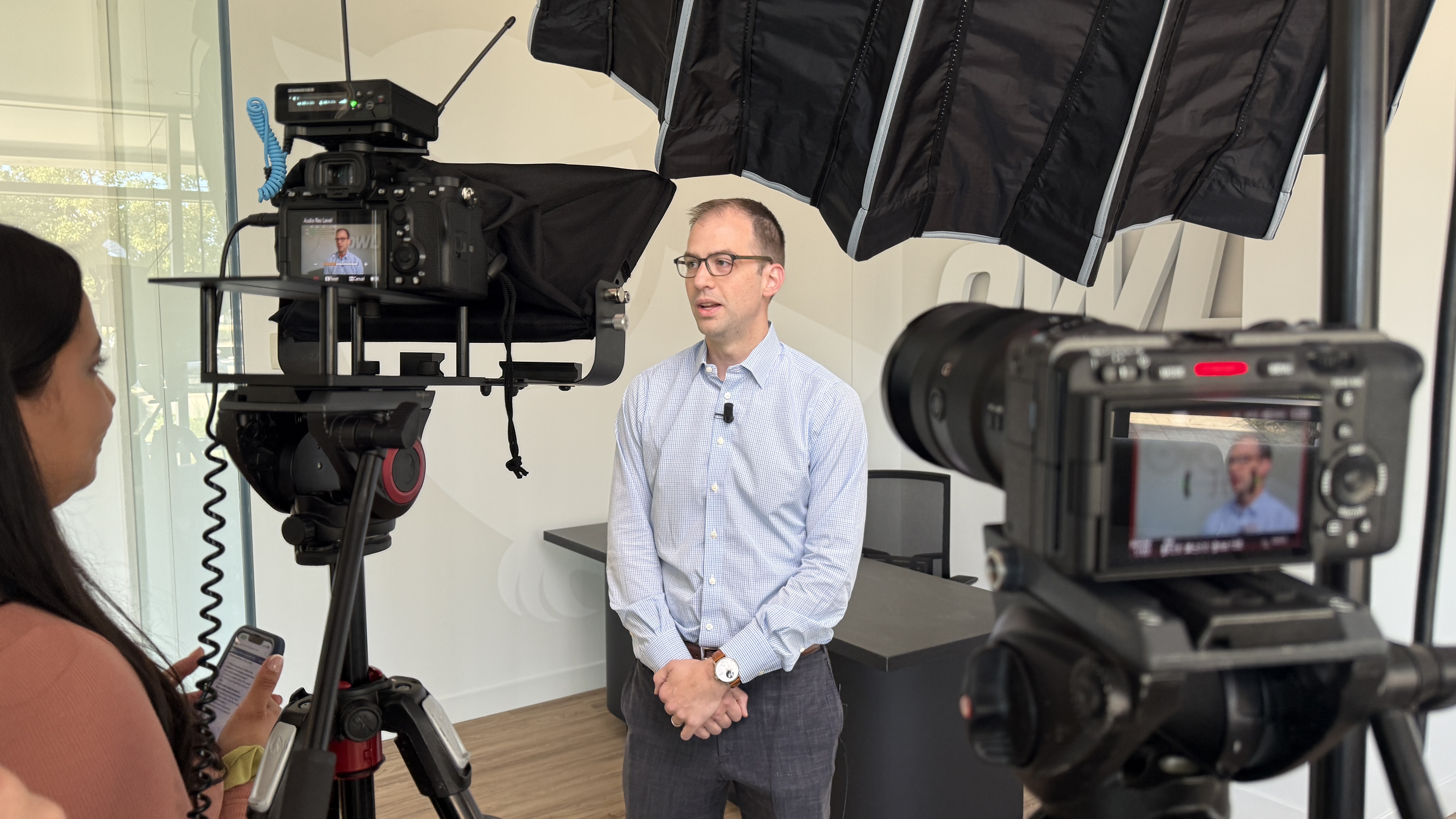 Corporate videographer filming a multi-camera interview with softbox lighting and wireless audio