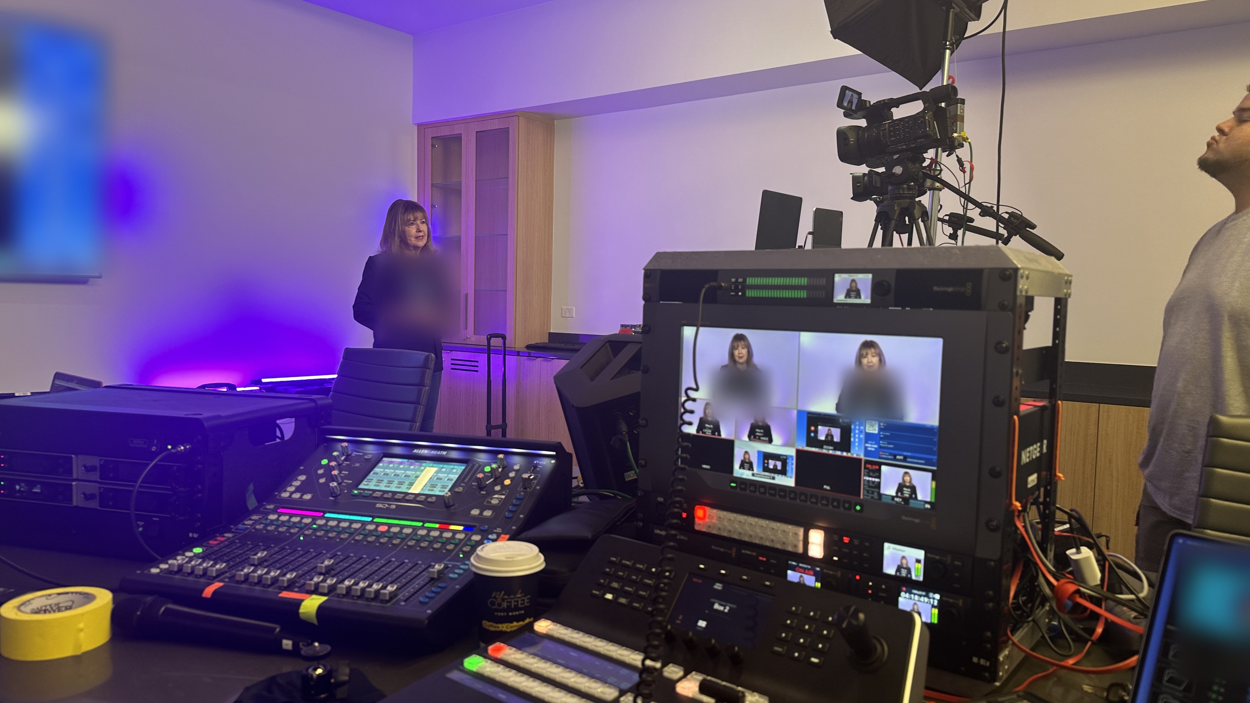 Producer's view of a corporate meeting webcast: switcher, audio mixer, and multiview monitor with a presenter on camera in a studio