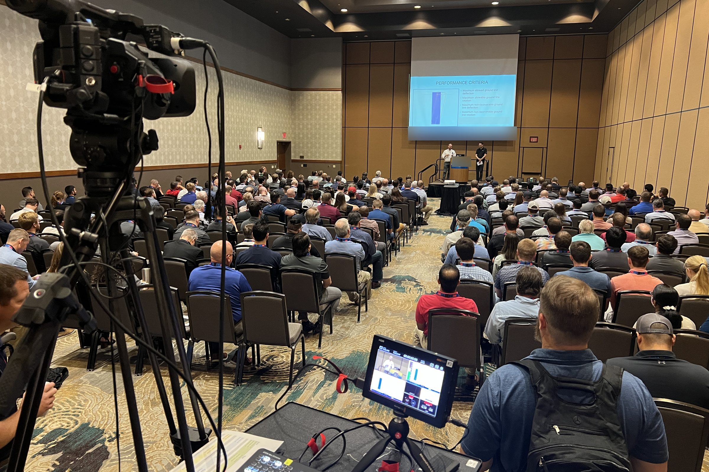 Camera operator and ATEM switcher at the back of a packed corporate conference room during a live event production
