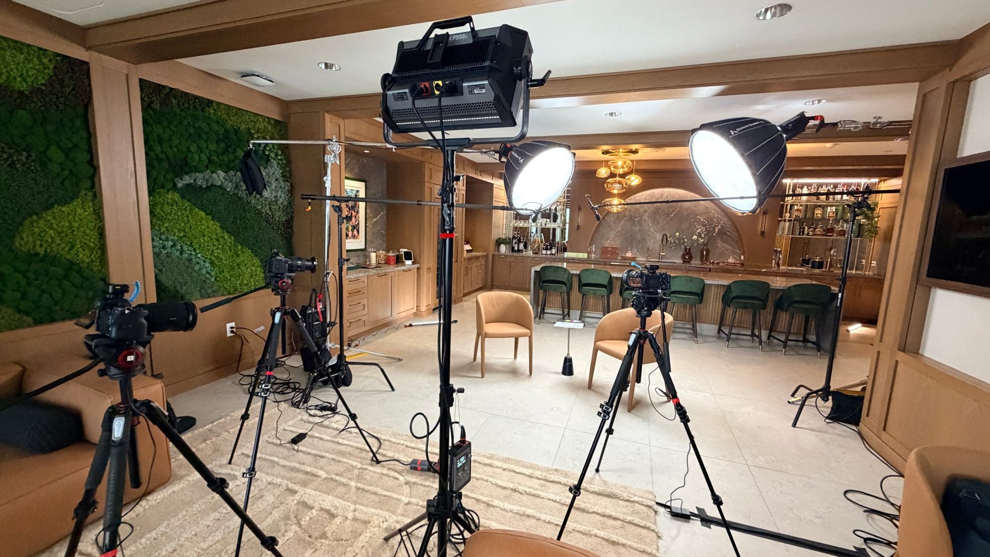 Three-camera video podcast production setup with two softbox key lights and boom mics in an office lounge