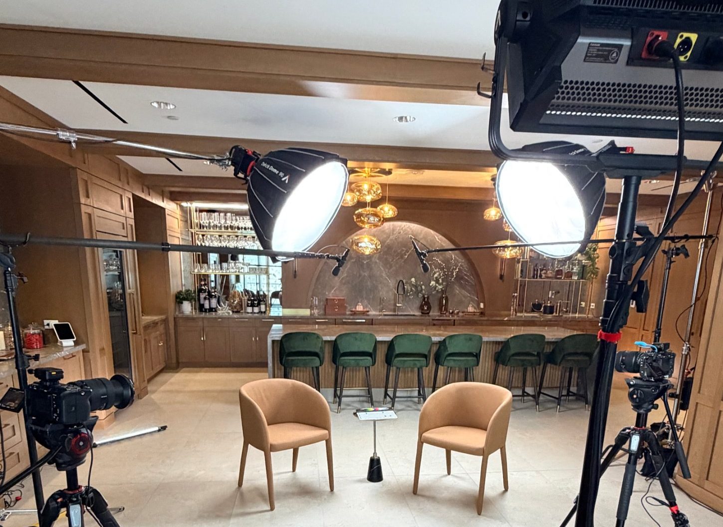 Finished three-camera interview set with cross-key softbox lighting, boom mics and two chairs ready for the podcast