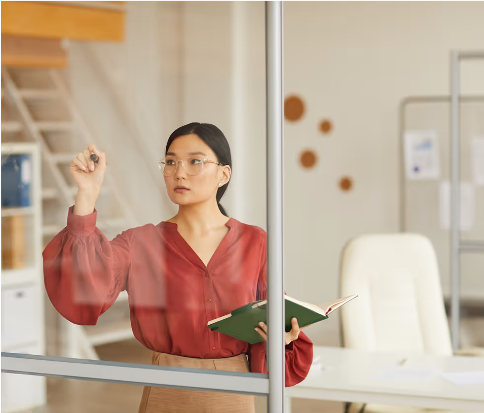 A woman standing in an office holding a book.