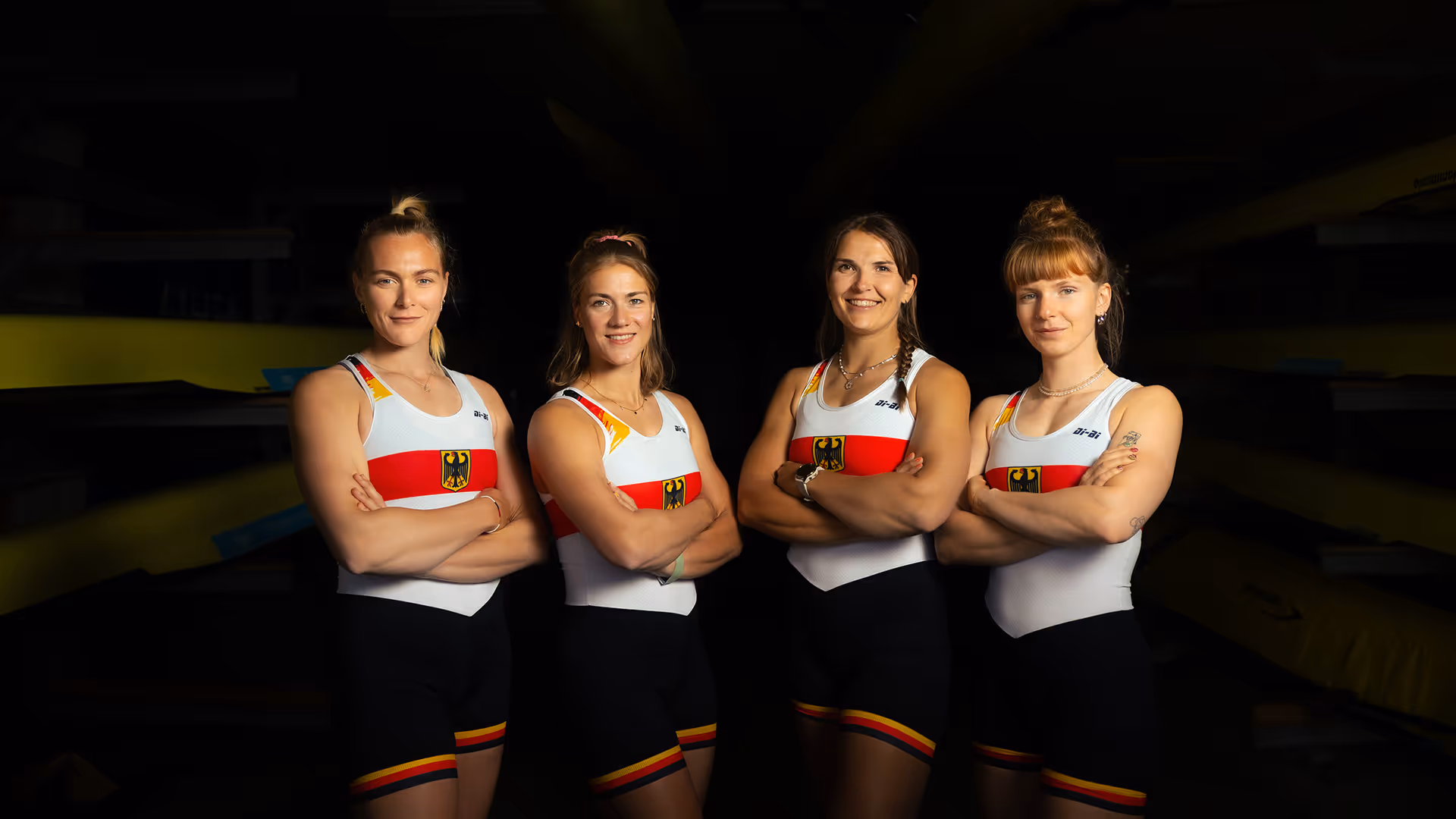 Gruppenfoto von vier Ruderinnen im Einteiler des deutschen Nationalteams, aufgenommen in einer Bootshalle.