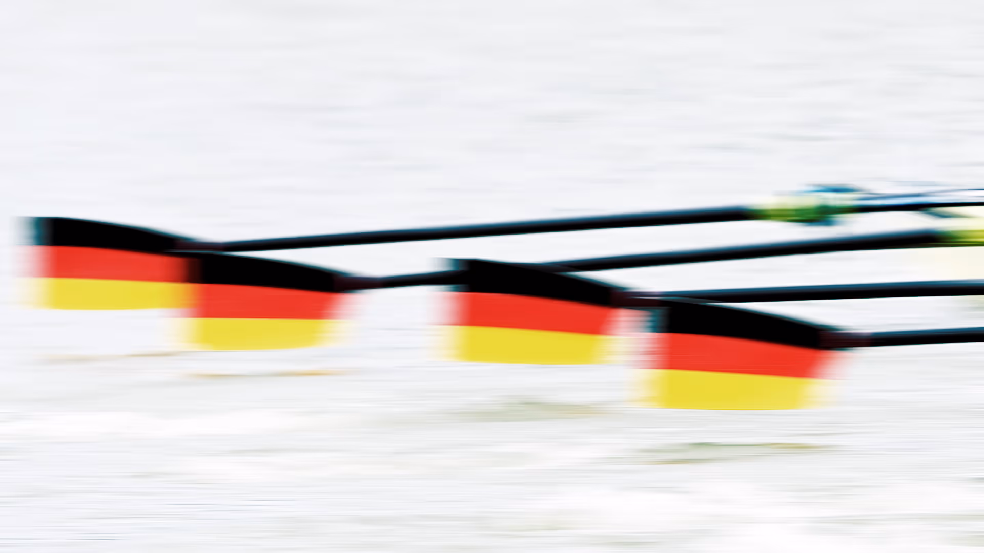 Ruderblätter mit schwarz-rot-goldener Deutschland-Flagge in Bewegung auf/über dem Wasser.