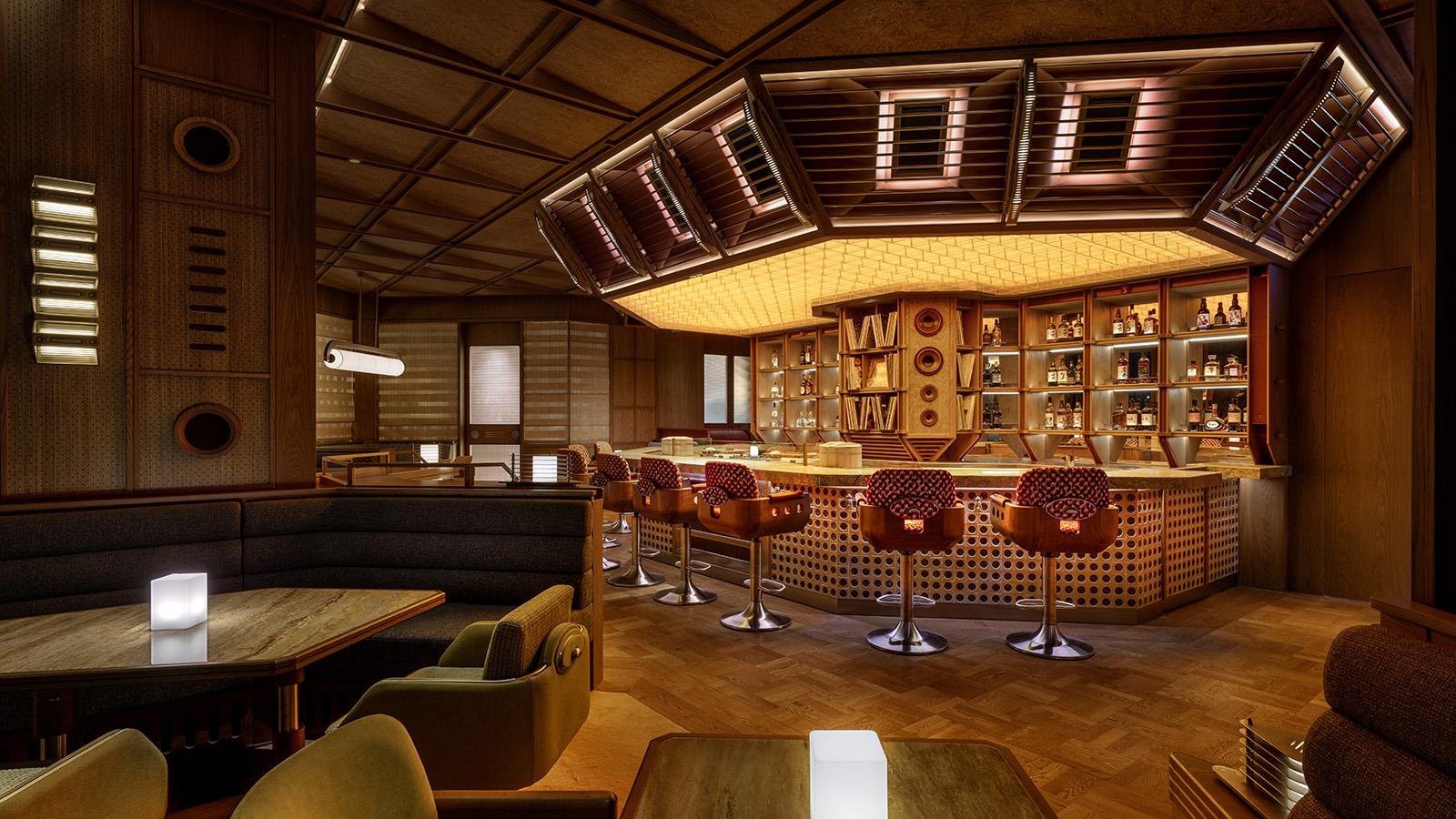 Modern listening bar interior at Saikindo in Abu Dhabi, showing a central bar with integrated speakers, vinyl storage, warm lighting, and acoustically designed wood finishes.