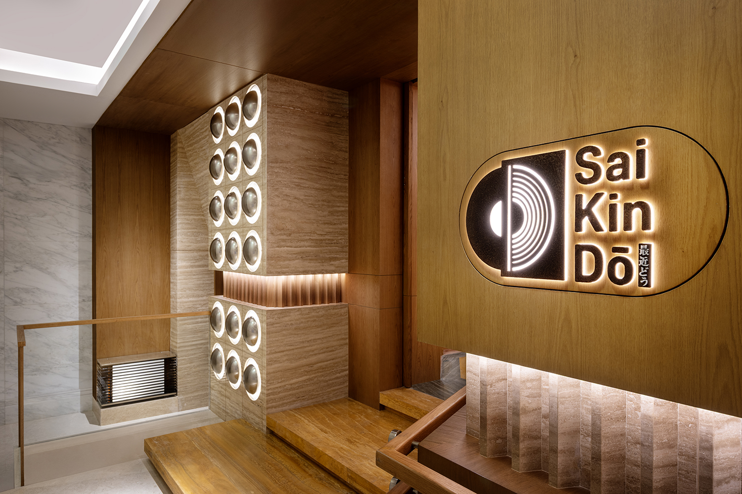 Entrance area of Saikindo listening bar at the Four Seasons Abu Dhabi, featuring branded signage, integrated sound system elements, and custom wood and stone finishes.