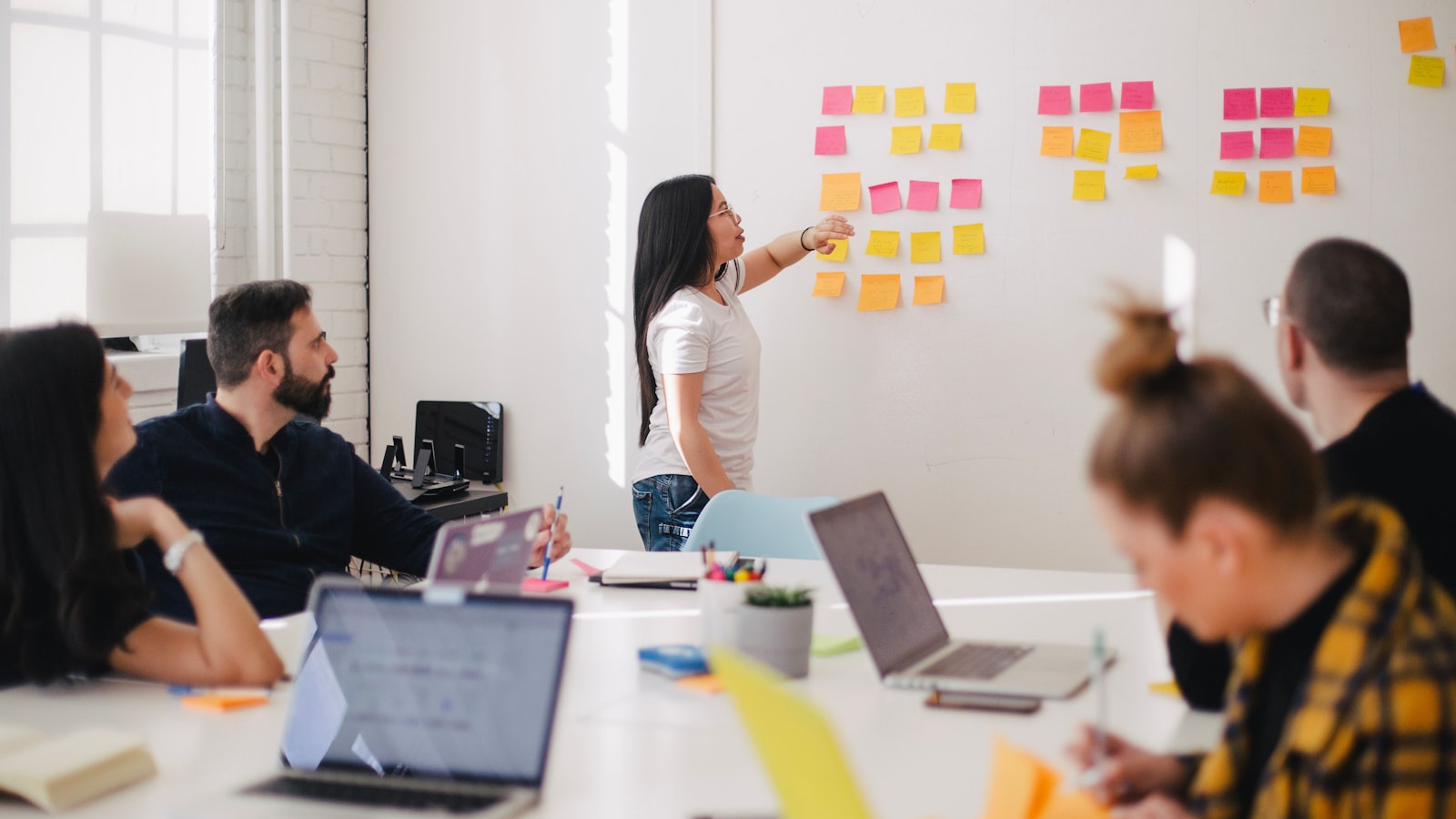 Équipe marketing en réunion de travail devant un mur de notes