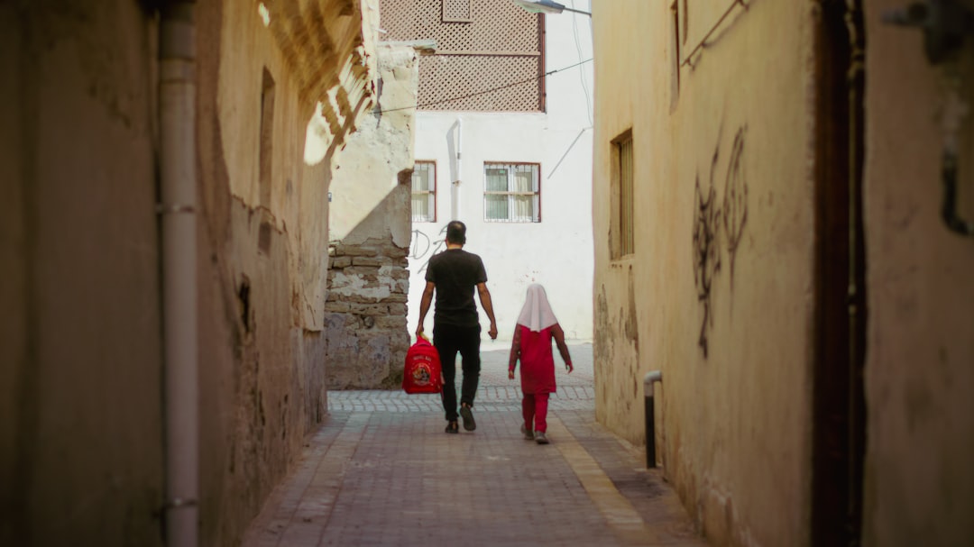 A man and a little girl walking down an alley way