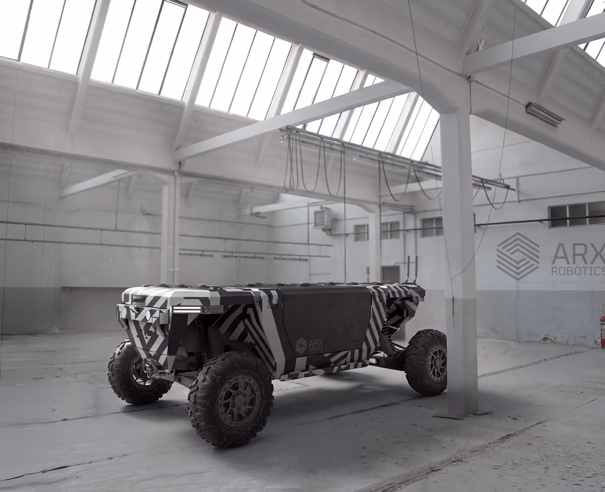 Off-road robotic vehicle with camouflage pattern inside a large industrial warehouse.