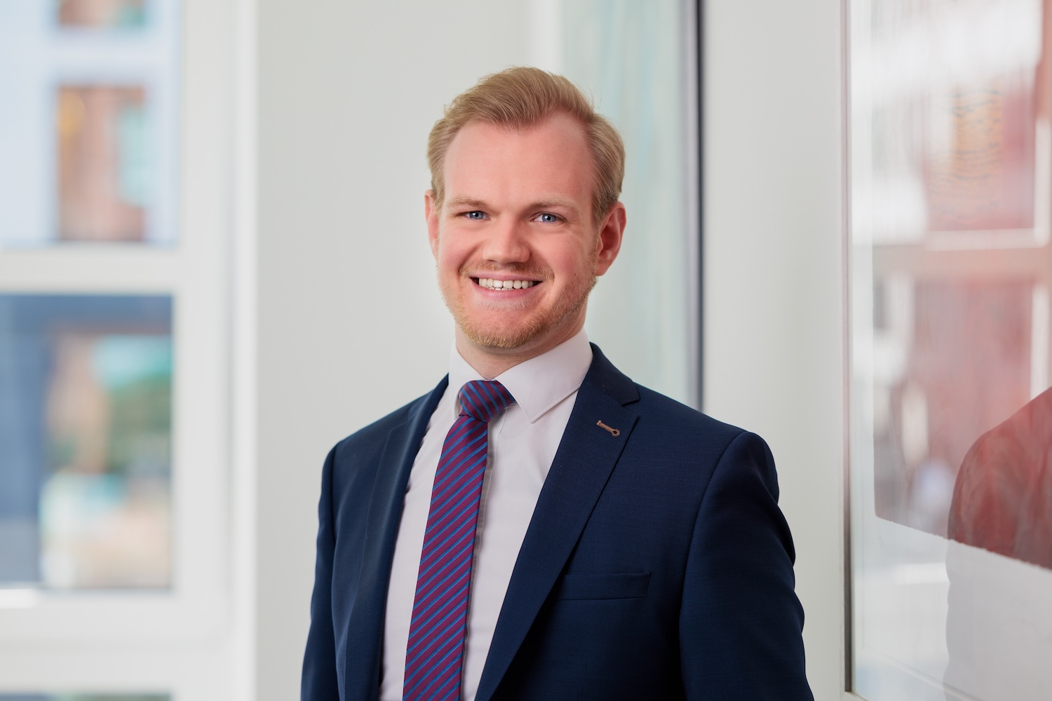 Porträt eines Mannes im Anzug, blond, lächelnd.