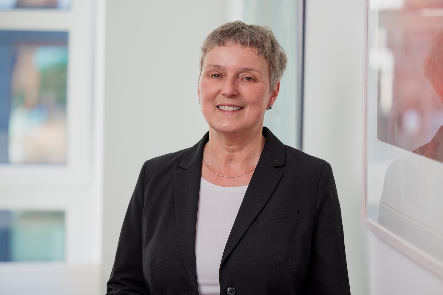 Porträt einer Frau im Business-Outfit, lächelnd.