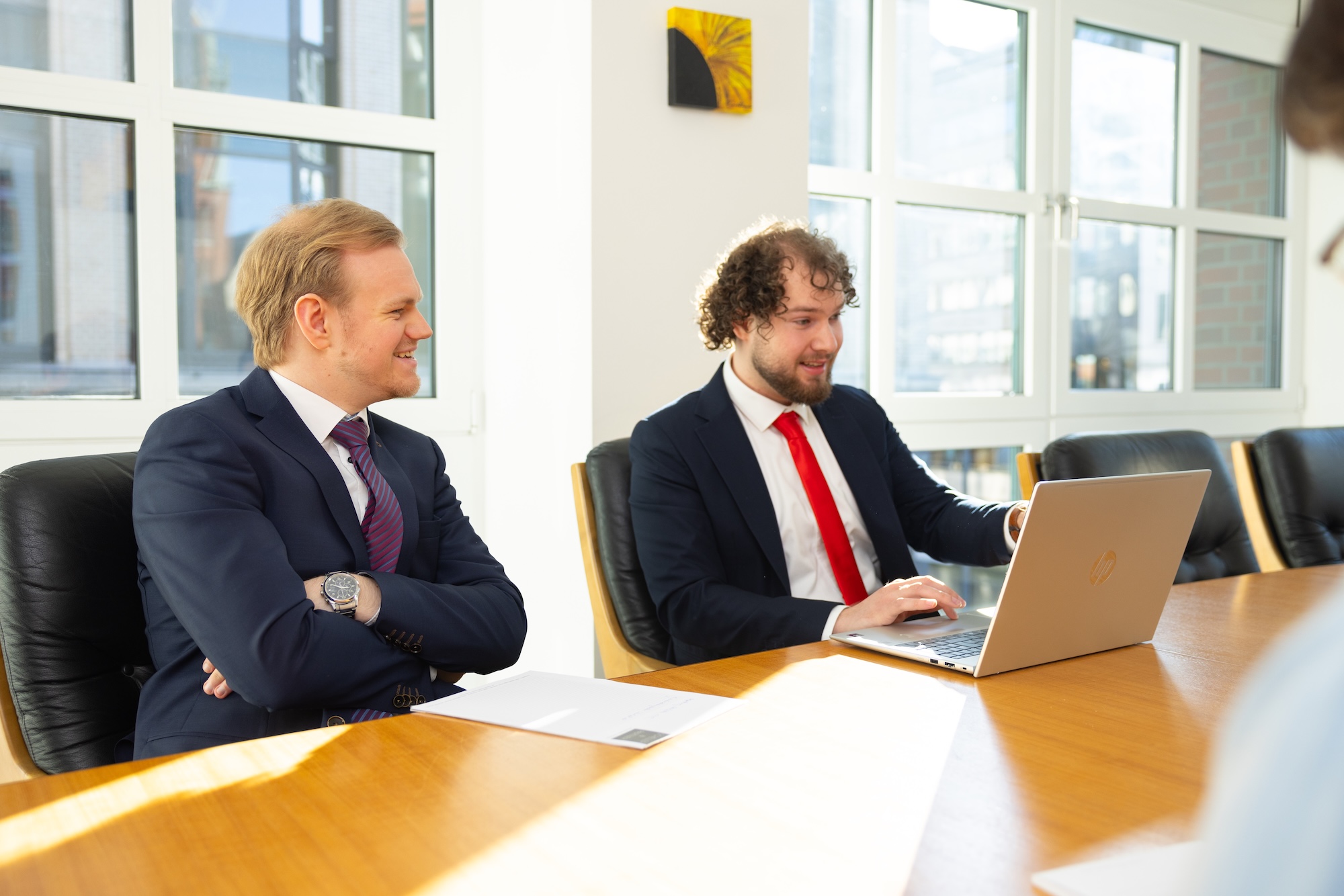 Drei Männer im Anzug im Büro im Gespräch.