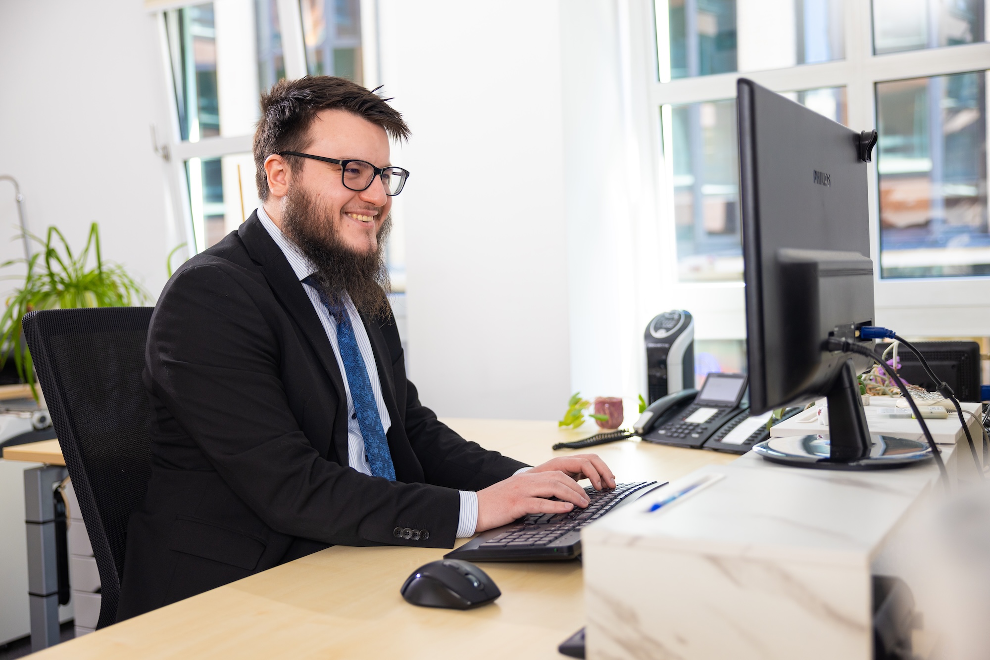 Zwei Männer im Anzug am Schreibtisch, arbeiten am Computer.