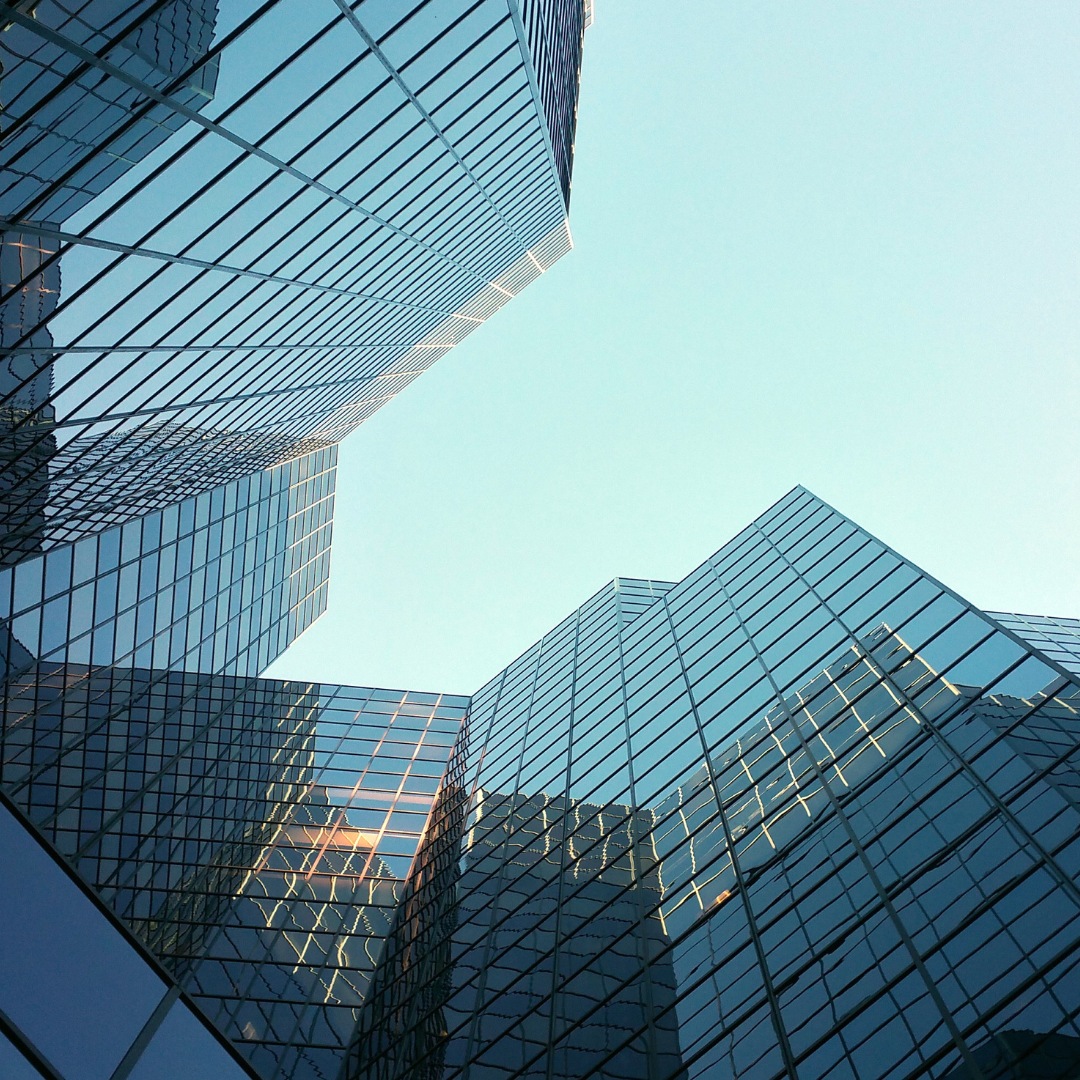 Blick nach oben auf moderne Glasfassaden von Hochhäusern.