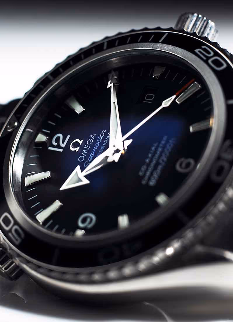 A close up photo of an stainless steel watch with an dark-electric blue face