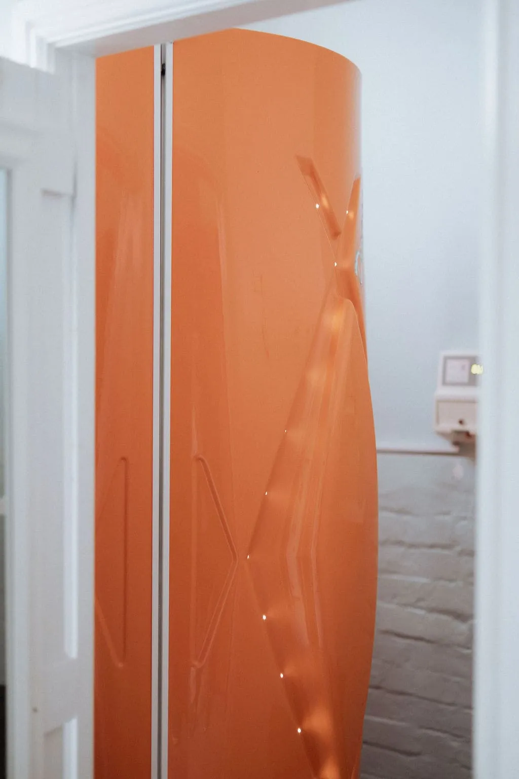 Vertical orange sunbed unit inside tanning room