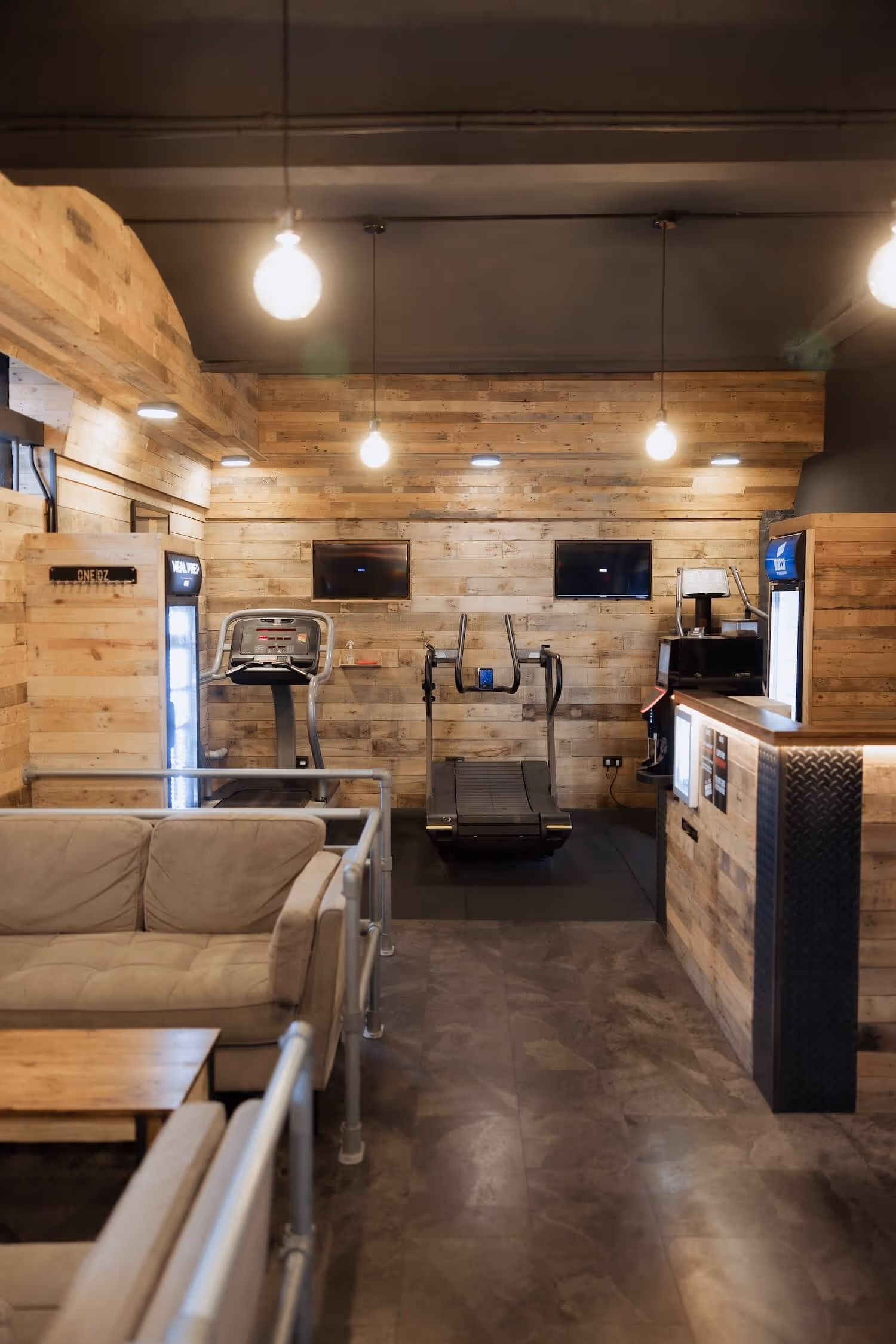 View of the digital advertising area inside ONE DZ gym in Derby with screens above the cardio equipment.