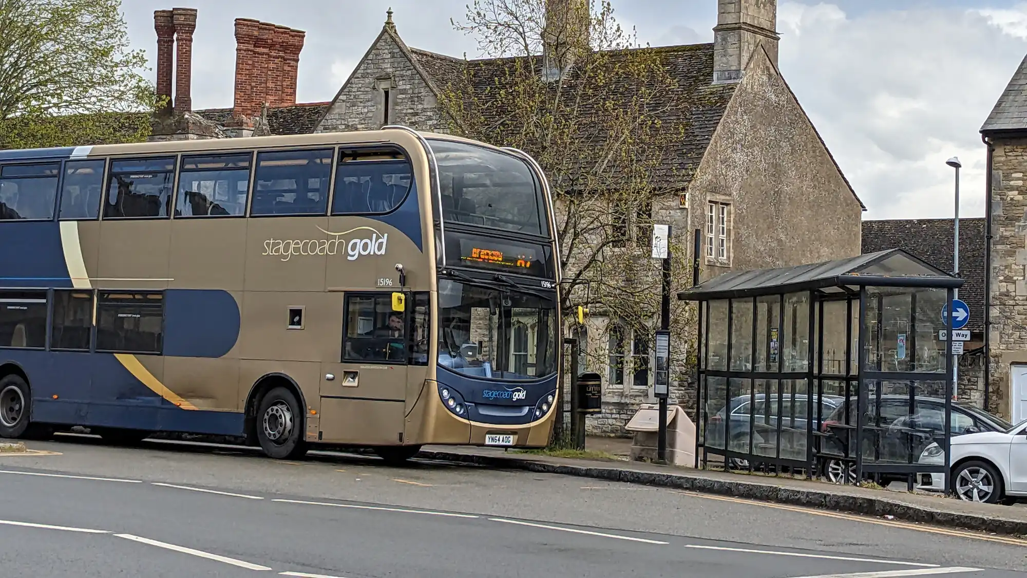 A bus arrriving at a bus stop in a rural setting